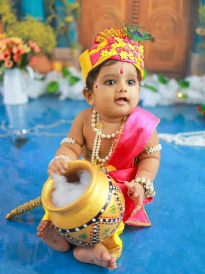Holding his pot of 'makhan', this baby Krishna looks ready for some playful mischief. The composition and lighting create a classic and beautiful portrait.