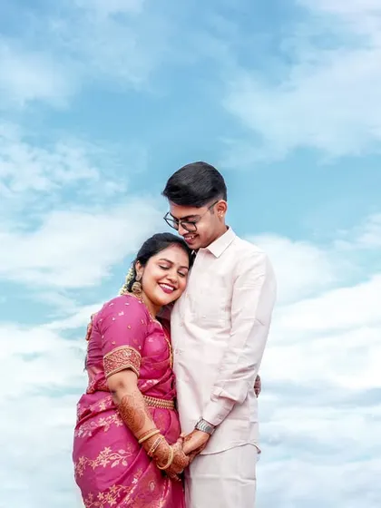 A tender moment with the bride resting her head on the groom's shoulder, set against the clouds.