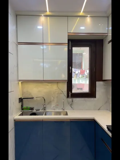 A closer look at the sink area of the blue and white kitchen. The high-gloss laminates are easy to clean and reflect light, making the kitchen feel bright and airy.