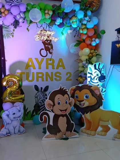 A lively jungle animal party for Ayra's 2nd birthday. This home decoration uses character cutouts, a large foil number '2', and a colorful balloon garland with green leaves.