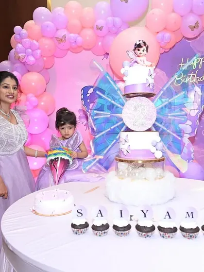A wide shot of the butterfly-themed dessert table, showing the beautiful coordination between the cake, cupcakes, and decorations.