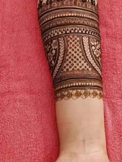 A detailed cuff-style design for the arm with geometric and traditional patterns.