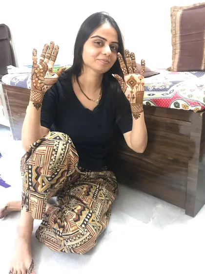 A happy client showing off her elegant party mehndi.