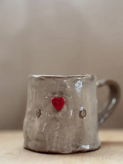 A student's first creation, this charmingly rustic mug with a bright red heart, shows the simple joy of making something with your own hands. It's perfectly imperfect and full of love.