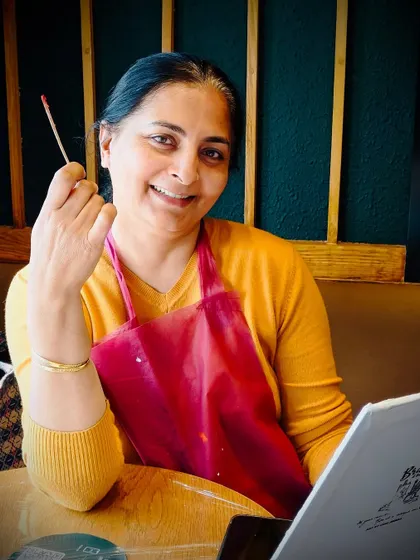 A happy participant holding her brush, ready to add more color to her canvas. The joy is in the process.