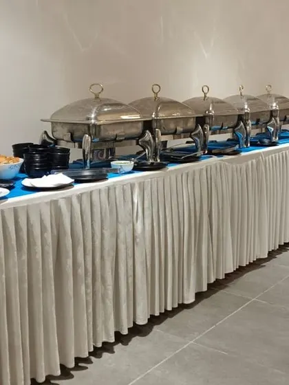 A neatly arranged buffet line with a clean white table skirt for a corporate lunch at Marg Online. We offer different presentation styles to match your event's tone.