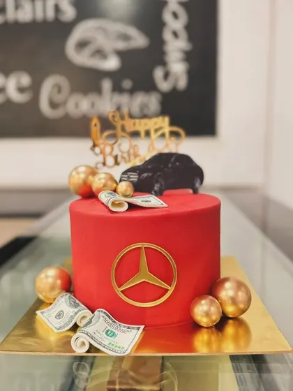 A bold red Mercedes-themed cake. This luxurious design features the iconic logo, edible money, and a car topper for a lavish celebration.