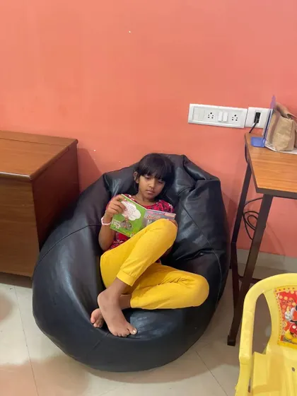 A duplicate shot of a girl enjoying her book in the bean bag chair, a popular spot in our library.