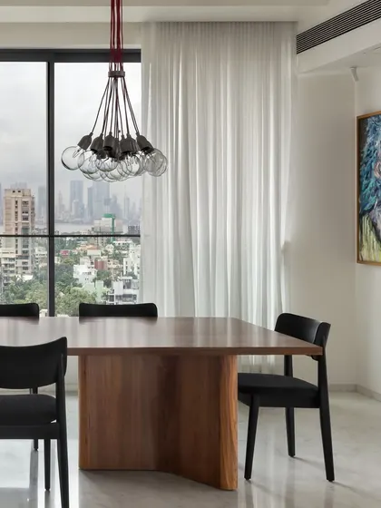 The dining room at the Bayview project was designed to celebrate the stunning city and sea views. A simple wooden table is paired with black chairs, ensuring the focus remains on the expansive window.