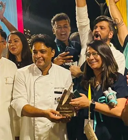 The winning team of a corporate food competition celebrates with the chef judge. These events foster healthy competition and teamwork, ending in a rewarding and celebratory moment.