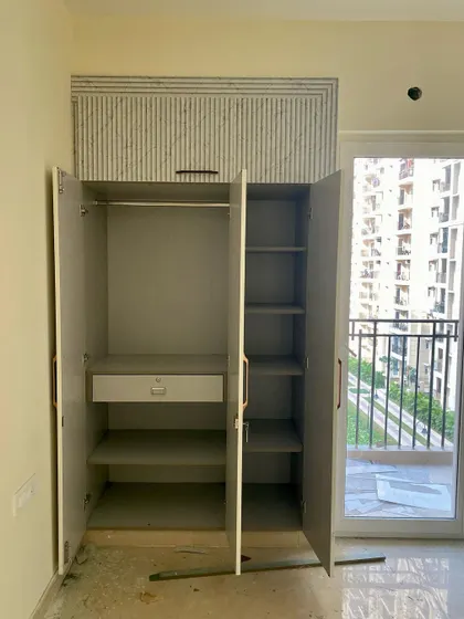 The interior view of the three-shutter wardrobe, showing the practical layout with a drawer and multiple shelves.