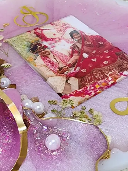 A work-in-progress shot of a resin frame for a newlywed couple. The photo is placed, and now I am arranging the preserved flowers and other decorative elements around it.