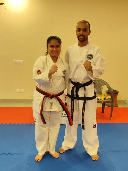 A student receives her red-stripe belt, marking her entry into the advanced stages of Taekwon-Do.