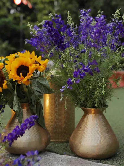 A simple yet stunning combination of sunflowers and purple delphiniums in brass vases.