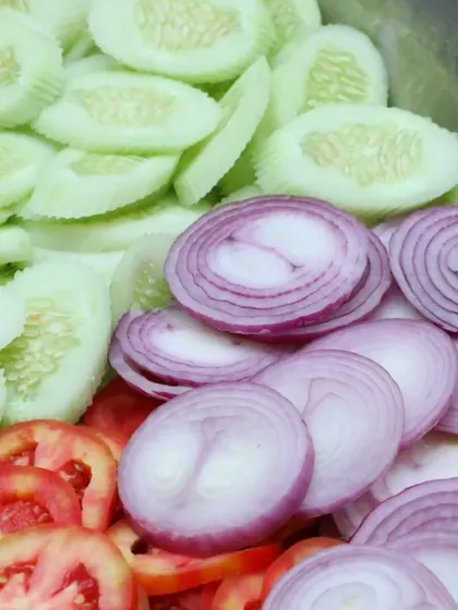 Freshly sliced cucumbers, tomatoes, and onions, a simple and refreshing salad to accompany any meal.