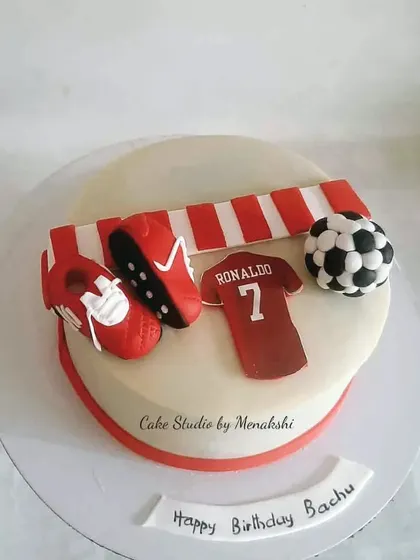 A Ronaldo themed cake for a football fan. This design includes his jersey, cleats, and a football, all in the classic red and white colours.