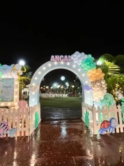 The entrance to the "Under The Sea" party, featuring a welcoming arch, picket fences, and cute sea creature cutouts, even on a rainy evening.