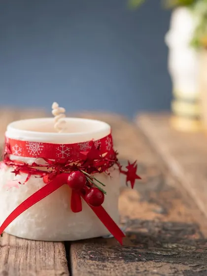 A simple and sweet white jar candle, decorated with a festive red ribbon for a touch of Christmas cheer.
