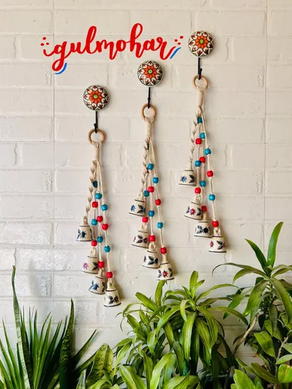 Our 'Symphony Chimes' in the 'Gulmohar' color variant, featuring red and blue wooden beads. These chimes are a beautiful combination of macrame knots and hand-painted ceramic bells, perfect for any decor style.