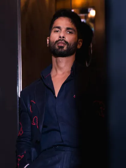 A moody, atmospheric shot of Shahid Kapoor. The subtle red embroidery on his dark suit adds a unique and personal touch.