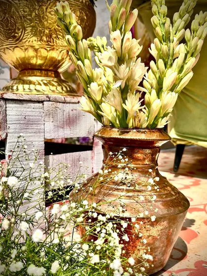 Close-up of decor details, with tuberoses in a rustic brass pot, adding a touch of traditional fragrance and beauty.