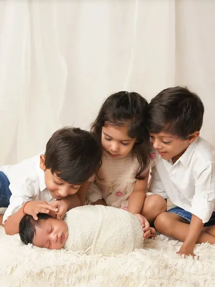 Three older siblings gather around their new baby brother, looking on with love and curiosity. Capturing the first meeting of the "crew" is always a special honor.