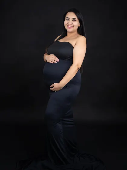 A simple and classic solo portrait against a black background. The focus is entirely on the mom-to-be and her beautiful baby bump.