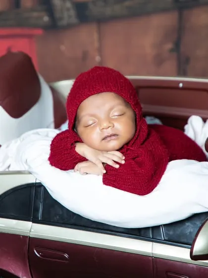A close-up of our sleepy mechanic, resting in his toy car. The red knit outfit adds a pop of colour to this garage-themed newborn session.