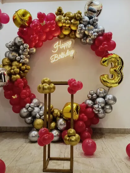A vibrant 3rd birthday celebration with a red, gold, and silver theme. This circular balloon arch is a showstopper, complete with a neon sign and number balloon.