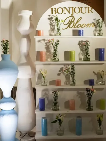 The 'Bonjour Bloom' corner, a modern take on a flower display with clean white shelves, minimalist vases, and colorful candles.