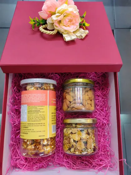 A healthy yet delicious hamper option in a striking red box. It contains jars of gourmet popcorn, roasted almonds, and muesli, perfect for health-conscious recipients.