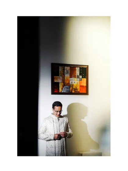 A dramatic portrait of the groom getting ready, using shadow and light to create a moody and stylish shot.