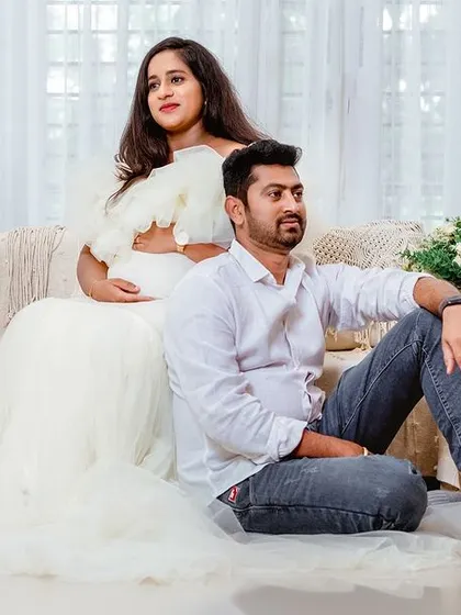 A modern, stylish pose for the expecting couple. The boho-chic studio decor, with its pampas grass and candles, provides a trendy and warm atmosphere.