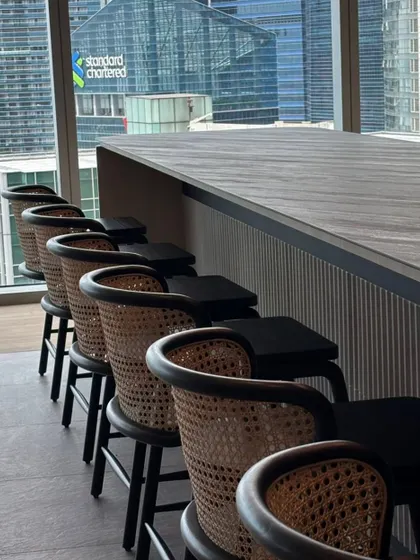 A set of custom bar stools designed for a corporate lounge overlooking the city. These stools feature a dark wood finish and intricate cane backrests, combining durability for high-traffic areas with a sophisticated aesthetic.