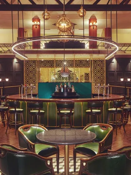 For the Karnataka Golf Association's bar, I designed a lighting scheme to create a sophisticated and moody atmosphere. This central view highlights the custom ring light fixture over the bar, which acts as a modern centerpiece, while carefully placed downlights make the green leather chairs and checkered floor pop.