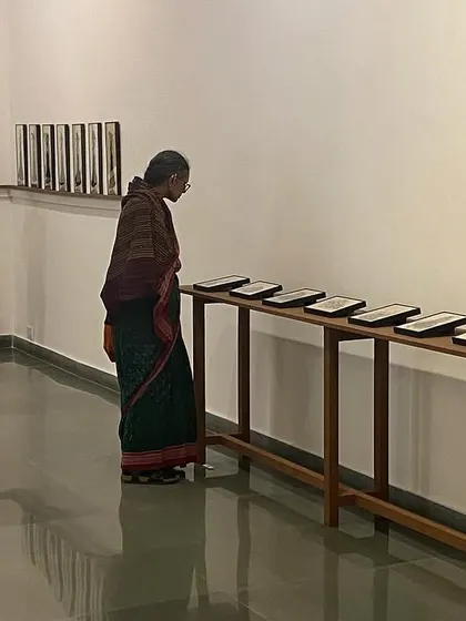 A visitor examining the row of reverse paintings, each telling a part of a larger story.