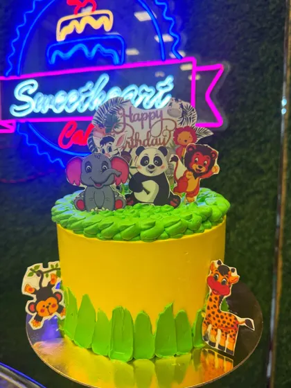 A jungle theme cake full of cute animals like an elephant, panda, and lion. The bright green and yellow colors create a cheerful and wild setting for a fun birthday party.