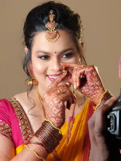 A playful behind-the-scenes shot. This captures the fun of the getting-ready process, showing the bride's genuine smile as she poses for the camera.