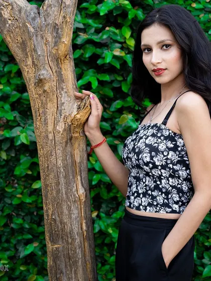 A female model posing against a tree trunk and a wall of green ivy. This composition uses natural elements to frame the subject, resulting in a classic and engaging outdoor portrait.