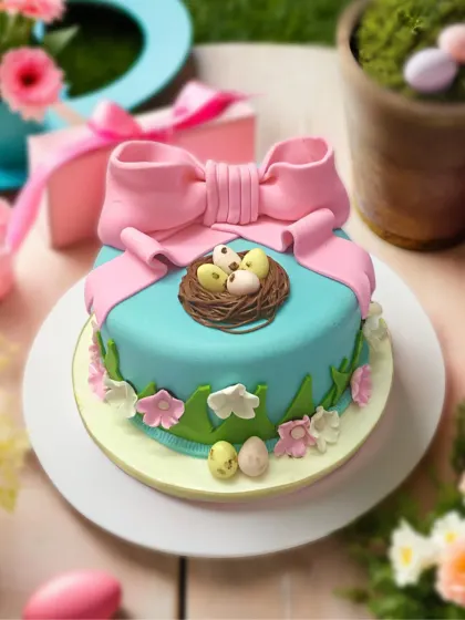 An adorable Easter cake with a big pink bow and a bird's nest full of chocolate eggs. It’s all about sweet spring surprises.
