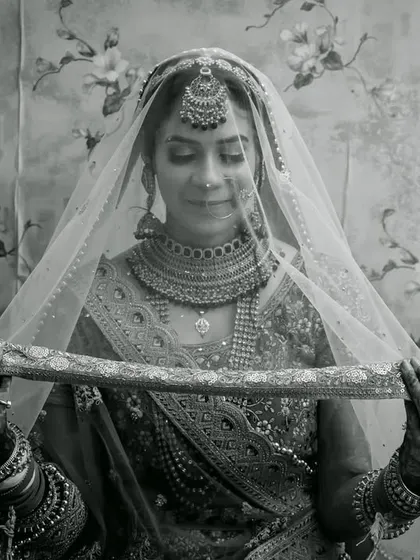 A classic black and white bridal portrait, with the bride gently holding her veil, creating a look of timeless elegance.
