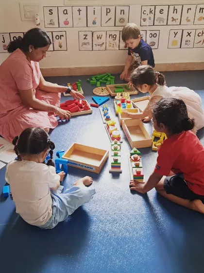 Our classroom is set up for collaborative building projects. Here, children and an educator work together with different block sets, sharing ideas and creating a complex town scene.