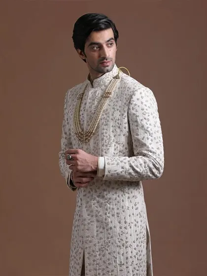 A closer view of the ivory sherwani, highlighting the subtle texture and intricate handwork. This modern fusion allows for both comfort and elegance.