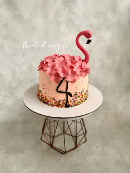 A pretty flamingo cake perfect for a summer party. This is a buttercream cake decorated with sprinkles, sugar hydrangeas, and a simple, elegant fondant flamingo topper.