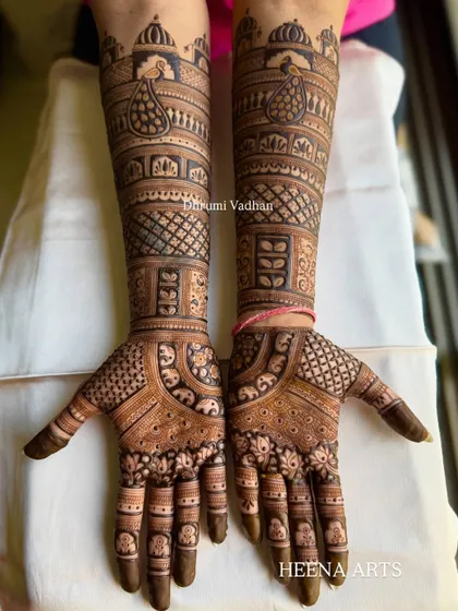 This full-hand design combines classic jharokha (window) elements with peacock motifs. The intricate checkerboard patterns add depth and texture to the overall bridal henna look.