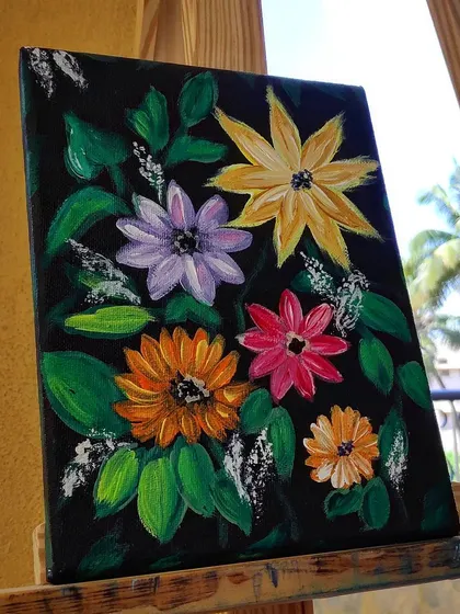 The bright floral painting displayed on an easel outdoors.
