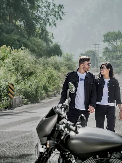 Walking hand-in-hand down a mountain road, with their bike waiting. This shot feels like a scene from a road trip movie, full of adventure and romance.