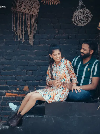 A relaxed and candid moment of the couple sharing a laugh. The rustic, dark brick wall and macrame hangings provide a trendy, bohemian vibe.