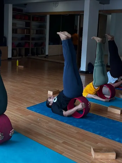 A duplicate of image 110, showing the supported shoulder stand on a yoga wheel.