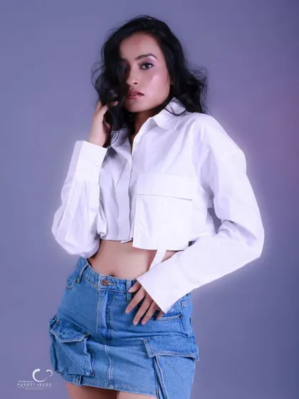 A confident and stylish pose against a soft purple background. The wind-blown hair adds a sense of movement and freedom.
